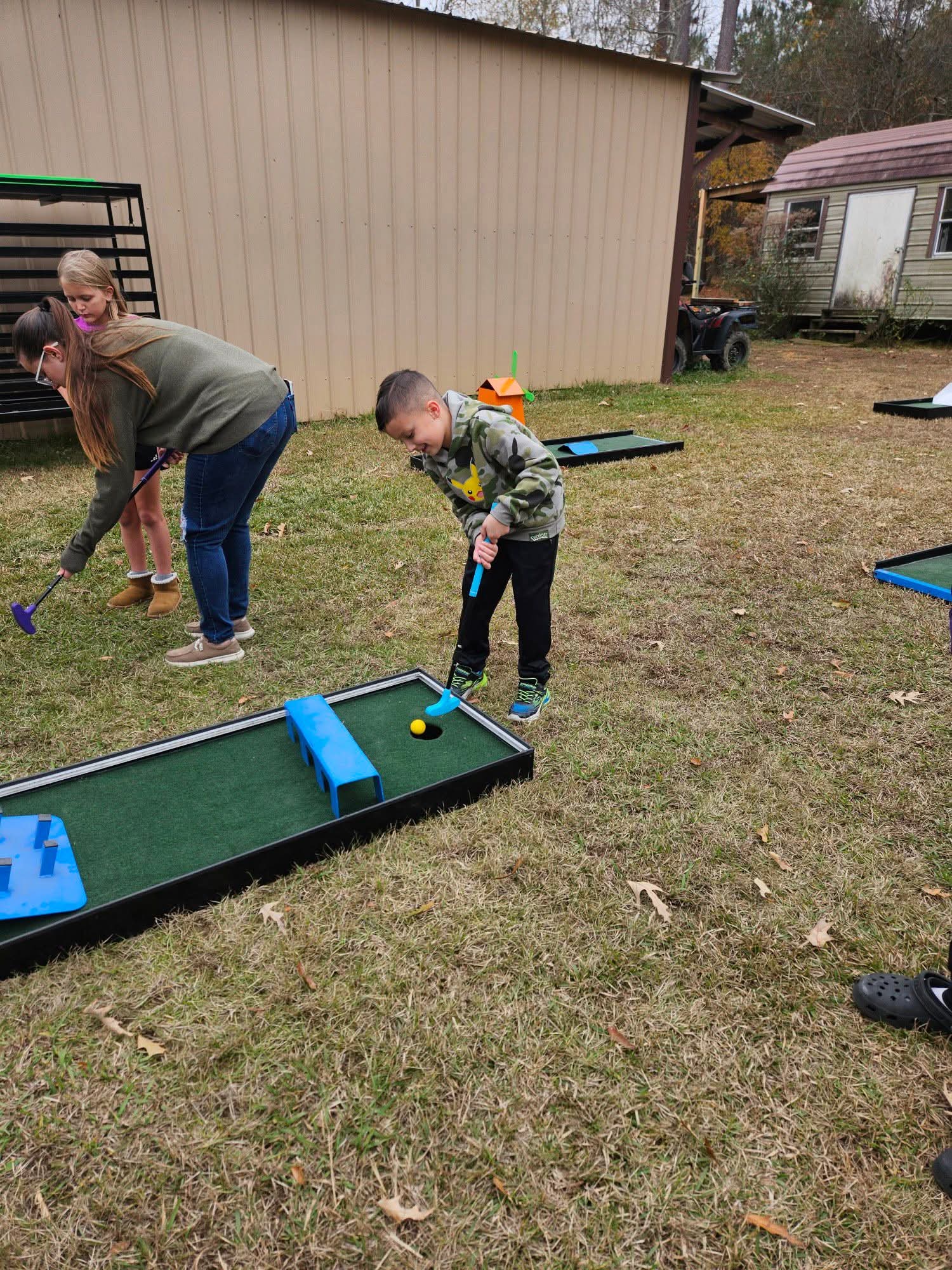 Children putting on a Putt Zone Texas course set up outdoors at a private party
